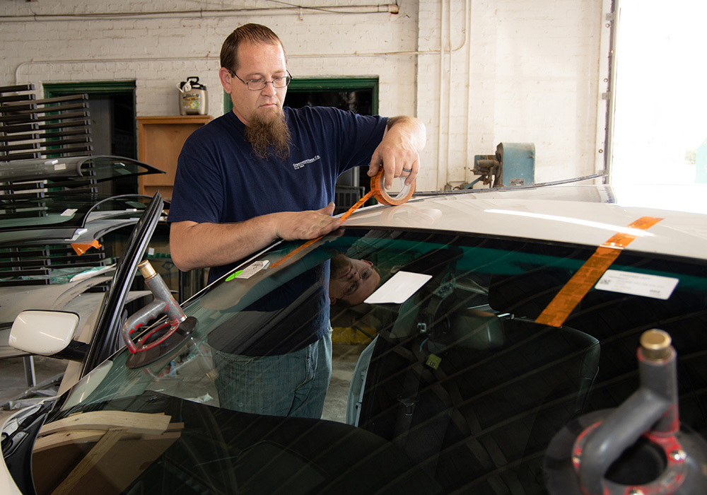 an image showing a Greenwood Glass Co employee working on auto glass repair